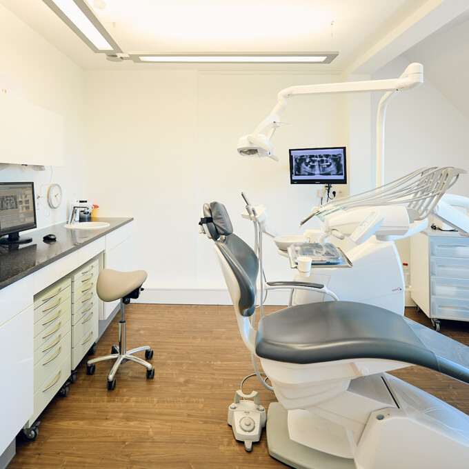 Helles Behandlungszimmer mit modernem Zahnarztstuhl, Deckenbild eines Frosches und professioneller medizinischer Ausstattung.