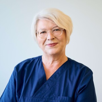 Portrait von Prophylaxeassistentin Sabine Wochner-Dutzi in dunkelblauem kasak vor einer wei&szlig;en Wand