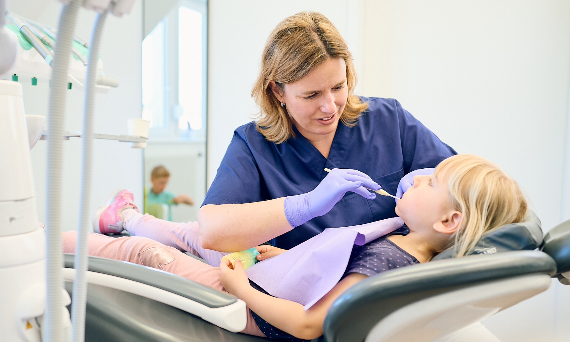 Einf&uuml;hlsame Zahnuntersuchung eines Kindes durch Zahn&auml;rztin Anna Rothe in einem hellen Behandlungszimmer.